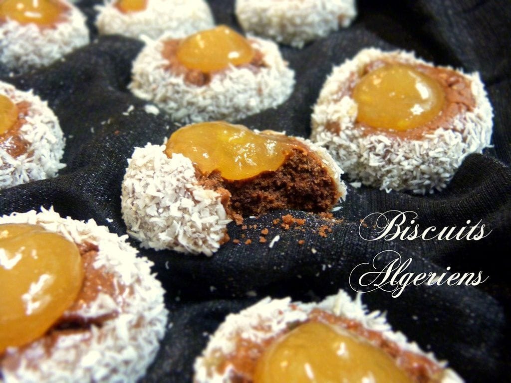 Thumbprint cookies au chocolat et confiture, biscuits de Noël fondants enrobés de noix de coco, disposés sur un tissu noir.